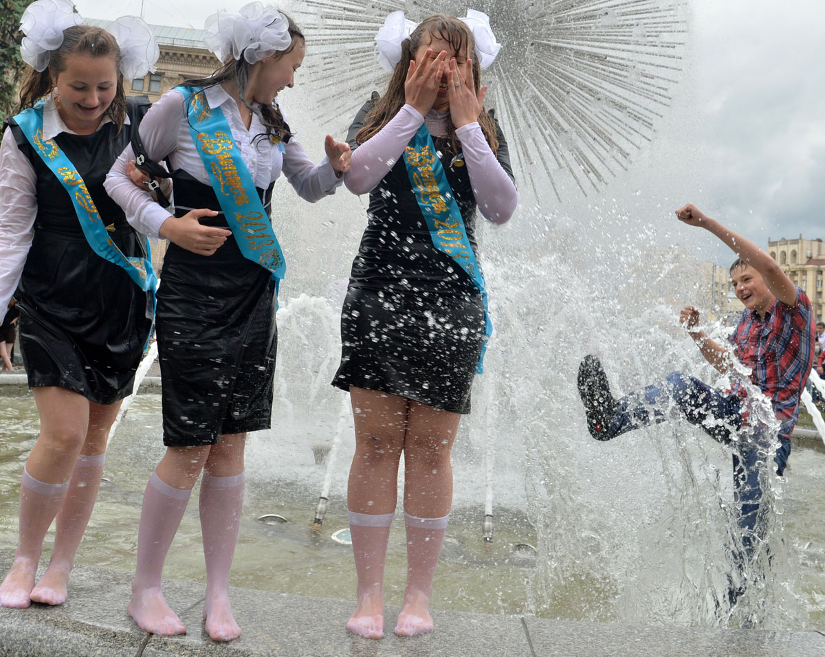 Современные выпускницы в школьной форме купаются в фонтанах