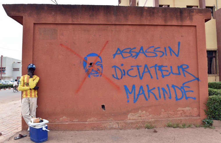 A man stands in front of a wall bearing a graffiti of ousted Burkinabese president Blaise Compaore and reading ''assassin, dictator, Makinde'' on the sidelines of negotiations on the transitional government after the ouster of Compaore in Burkina Faso, on November 12, 2014 in Ouagadougou. The army, which took power after president Blaise Compaore's exit following a popular uprising in response to his bid to extend his 27-year rule, is under heavy international pressure to quickly hand over to a civilian government. (Issouf Sanogo/AFP/Getty Images)