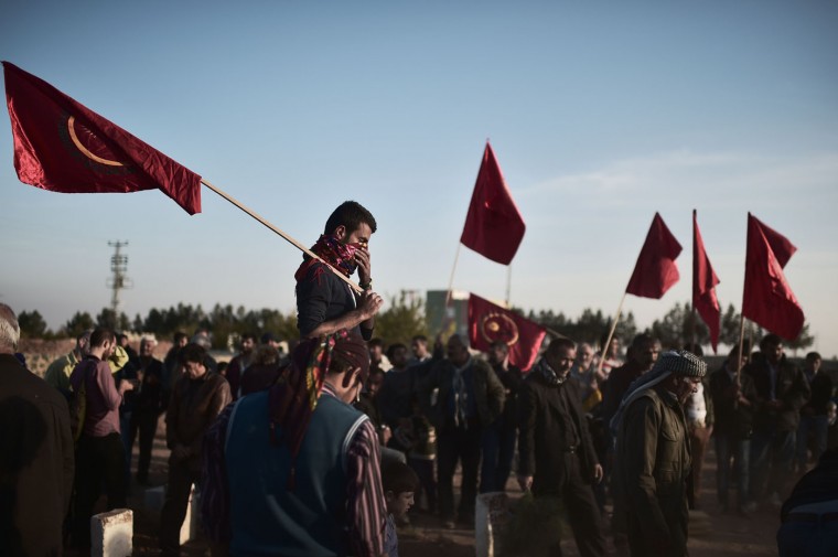 Kurdish people gather in the Turkish town of Suruc in the Sanliurfa province to attend the funeral of a People's Protection Units (YPG) fighter who died while fighting in the Syrian Kurdish flashpoint town of Kobane, also known as Ain al-Arab, on November 12, 2014. Kurdish forces fighting the Islamic State group in Kobane cut off a key supply route used by the jihadists, the Syrian Observatory for Human Rights said. (Aris Messinis/AFP/Getty Images)