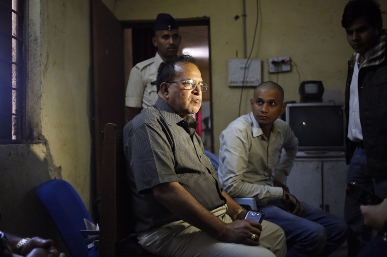 R.K.Gupta (L), a doctor who performed sterlisation surgeries at a government mass sterilisation "camp", sits at a police station as police and the media look on in Bilaspur, in the eastern Indian state of Chhattisgarh, November 13, 2014. Gupta, whose sterilisation of 83 women in less than three hours ended in at least a dozen deaths said on Thursday the express operations were his moral responsibility and blamed adulterated medicines for the tragedy. Gupta, who says he has conducted more than 50,000 such operations, denied that his equipment was rusty or dirty and said it was the government's duty to control the number of people that turned up at his family-planning "camp". (Anindito Mukherjee/Reuters)