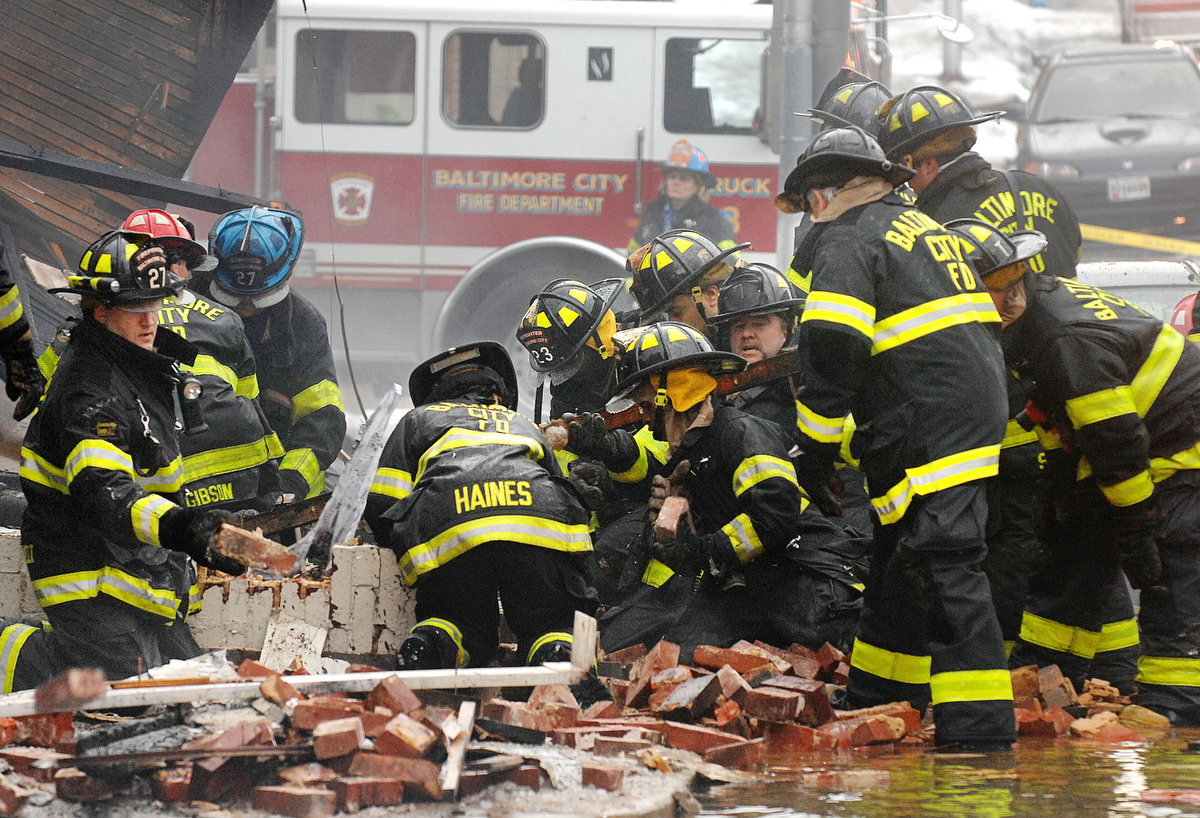 Baltimore City firefighters dig through debris from a rowhouse explosion on North ...