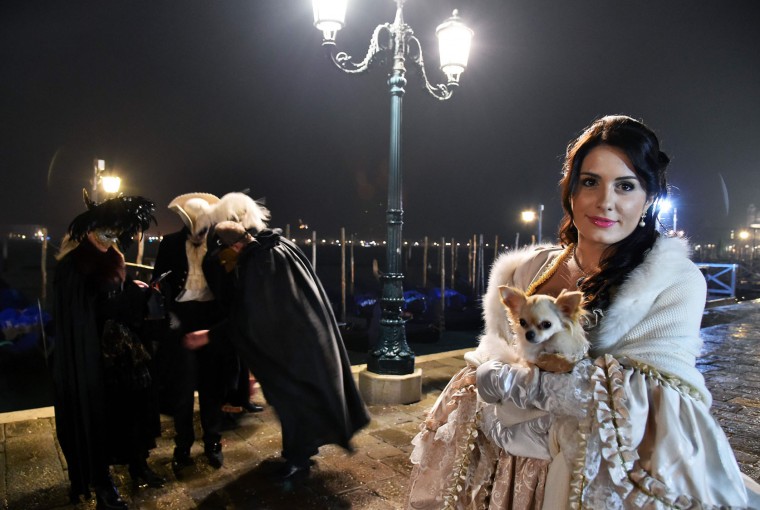 A costumed reveller poses in front of gondolas at St Mark's square (Piazza San Marco) during the Venice Carnival on January 30, 2016 in Venice. The 2016 edition of the Venice carnival is untitled " Creatum " and runs until February 9th. (Vincenzo Pinto/AFP/Getty Images)