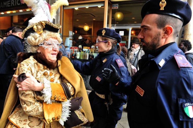 A masked woman goes through a security check in Venice, Italy, Sunday, Jan. 31, 2016. People attended the Venice Carnival, celebrated Saturday under heightened security following the sexual assaults on New Year's Eve in Cologne and the ongoing terror threat in Europe. Authorities have increased surveillance throughout the city, including the number of officers on patrol, both under-cover and in uniform. (AP Photo/Luigi Costantini)