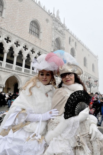 Two masked women pose in St. Mark's Square in Venice, Italy, Sunday, Jan. 31, 2016. Carnival-goers in Venice are being asked by police to momentarily lift their masks as part of new anti-terrorism measures for the annual festivities. Police are also examining backpacks and bags and using metal-detecting wands before revelers are allowed into St. Mark's Square, the heart of the Venetian carnival. (AP Photo/Luigi Costantini)