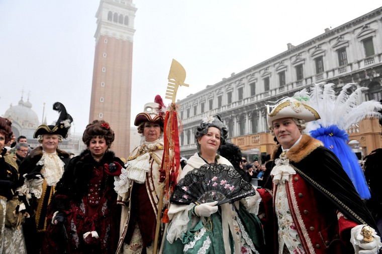 People wearing costumes pose in St. Mark's Square in Venice, Italy, Sunday, Jan. 31, 2016. Carnival-goers in Venice are being asked by police to momentarily lift their masks as part of new anti-terrorism measures for the annual festivities. Police are also examining backpacks and bags and using metal-detecting wands before revelers are allowed into St. Mark's Square, the heart of the Venetian carnival. (AP Photo/Luigi Costantini)