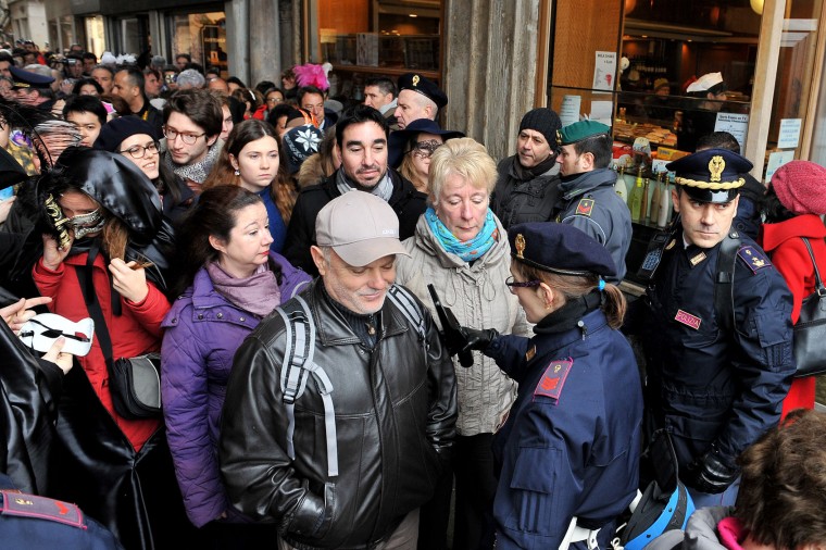 People go through security checks in St. Mark's Square, in Venice, Sunday, Jan. 31, 2016. Carnival-goers in Venice are being asked by police to momentarily lift their masks as part of new anti-terrorism measures for the annual festivities. Police are also examining backpacks and bags and using metal-detecting wands before revelers are allowed into St. Mark's Square, the heart of the Venetian carnival. (AP Photo/Luigi Costantini)