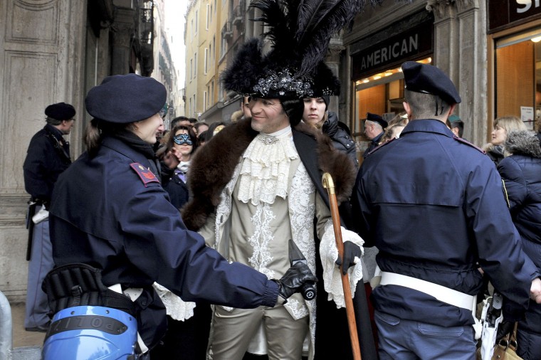 A police officer checks a man wearing a carnival costume in Venice, Italy, Sunday, Jan. 31, 2016. Carnival-goers in Venice are being asked by police to momentarily lift their masks as part of new anti-terrorism measures for the annual festivities. Police are also examining backpacks and bags and using metal-detecting wands before revelers are allowed into St. Mark's Square, the heart of the Venetian carnival.(AP Photo/Luigi Costantini)