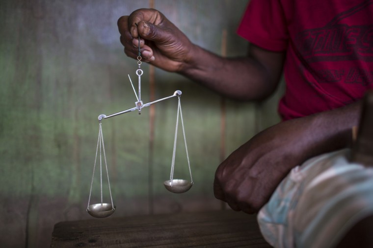 In this Nov. 15, 2015 photo, an artisanal miner weighs diamonds in Areinha, Minas Gerais state, Brazil. Diamond mining sounds like a thing of the past to many Brazilians. But here, in areas that are hard to access, thousands of rural miners still survive and feed their families. (AP Photo/Felipe Dana)