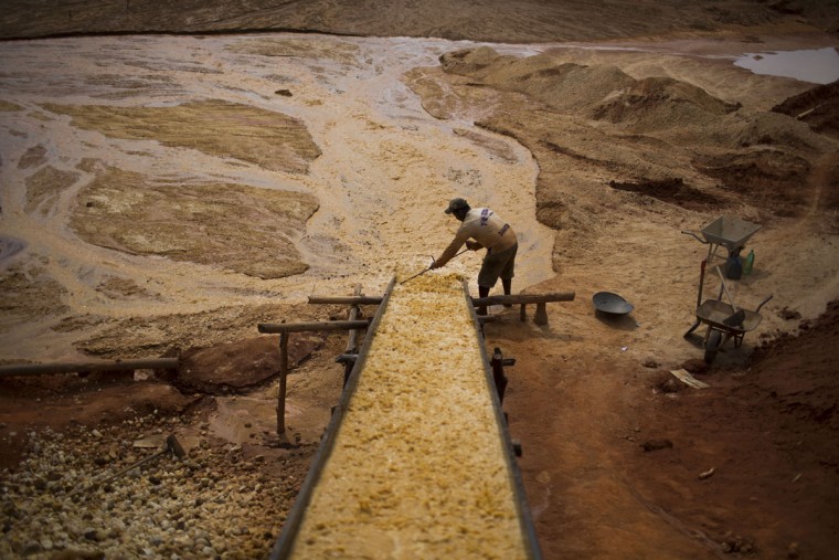 In this Nov. 14, 2015 photo, an artisanal diamond miner separates large rocks from smaller ones at an abandoned mine in Areinha, Minas Gerais state, Brazil. The mining process can take weeks. First miners excavate the soil. Once the layer of gravel is reached which can be as deep as 50 meters, they extract the rocks with the help of small pumps powered by old truck engines and begin the manual separation process to filter the small rocks, and if lucky, the diamonds. (AP Photo/Felipe Dana)