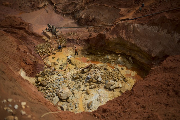 In this Nov. 14, 2015 photo, artisanal diamond miners use a water pump to separate rocks at an abandoned mine in Areinha, Minas Gerais state, Brazil. The devastated area known as Areinha is a no manís land where small groups of rural miners try their luck in the craters left behind by multinational mining companies. (AP Photo/Felipe Dana)