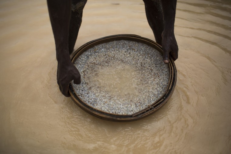 In this Nov. 17, 2015 photo, an artisanal miner searches for diamonds at an abandoned mine in Areinha, Minas Gerais state, Brazil. The devastated area known as Areinha is a no manís land where small groups of rural miners try their luck with artisan techniques, using wooden knives, metal pans, large water pumps and no infrastructure. (AP Photo/Felipe Dana)