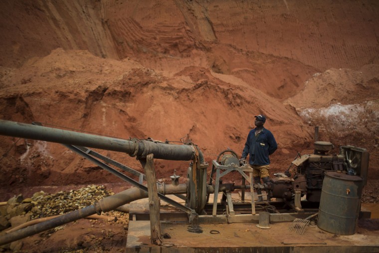 In this Nov. 14, 2015 photo, an artisinal miner controls a water pump in a crater left behind by giant diamond mining companies in Areinha, Minas Gerais state, Brazil. Today the devastated area known as Areinha is a no manís land where small groups of rural miners try their luck with artisan techniques, using wooden knives, metal pans, large water pumps and no infrastructure. (AP Photo/Felipe Dana)