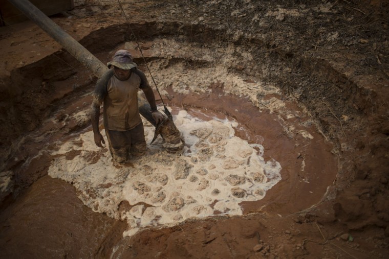 In this Nov. 13, 2015 photo, an artisanal miner uses a pump to pull water and rocks inside a crater left behind by giant diamond mining companies, now used by rural miners in Areinha, Minas Gerais state, Brazil. Today the devastated area known as Areinha is a no manís land where small groups of rural miners try their luck with artisan techniques, using wooden knives, metal pans, large water pumps and no infrastructure. (AP Photo/Felipe Dana)