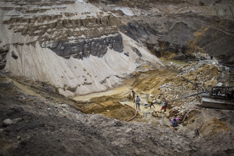 In this Nov. 11, 2015 photo, artisanal miners work in a crater left behind by giant diamond mining companies in Areinha, Minas Gerais state, Brazil. Today the devastated area known as Areinha is a no manís land where small groups of rural miners try their luck with artisan techniques, using wooden knives, metal pans, large water pumps and no infrastructure. (AP Photo/Felipe Dana)