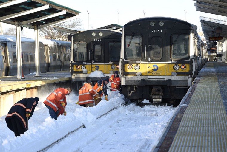 Workers clear the tracks of snow at the Port Washington branch of the 