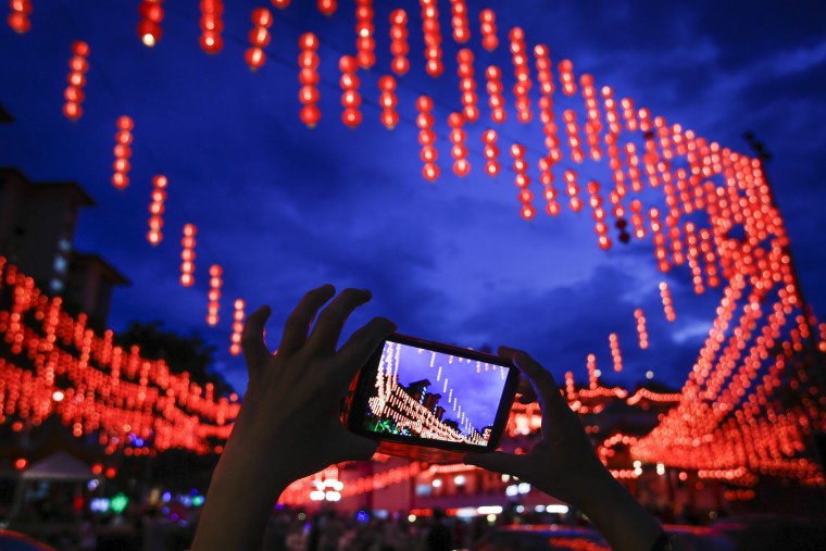 A Malaysian ethnic Chinese woman takes a souvenir photograph of illuminated traditional Chinese lanterns on the eve of Lunar New Year in Kuala Lumpur, Malaysia, Sunday, Feb. 7, 2016. The Lunar New Year which falls on Feb. 8 this year marks the Year of the Monkey in the Chinese calendar. (AP Photo/Joshua Paul)