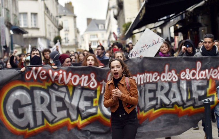 A young woman shouts slogans in front of a banner as thousands of people demonstrate on March 9, 2016 in Nantes, western France, as part a nationwide day of protest against proposed labour reforms. France faced a wave of protests against deeply unpopular labour reforms that have divided an already-fractured Socialist government and raised hackles in a country accustomed to iron-clad job security. (AFP / Loic Venance)