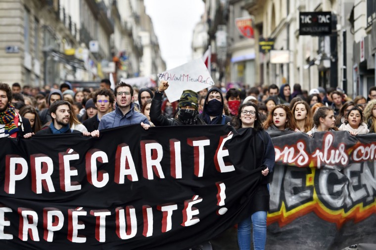 Young people hold a banner as thousands of people demonstrate on March 9, 2016 in Nantes, western France, as part a nationwide day of protest against proposed labour reforms. France faced a wave of protests against deeply unpopular labour reforms that have divided an already-fractured Socialist government and raised hackles in a country accustomed to iron-clad job security. (AFP / Loic Venance)
