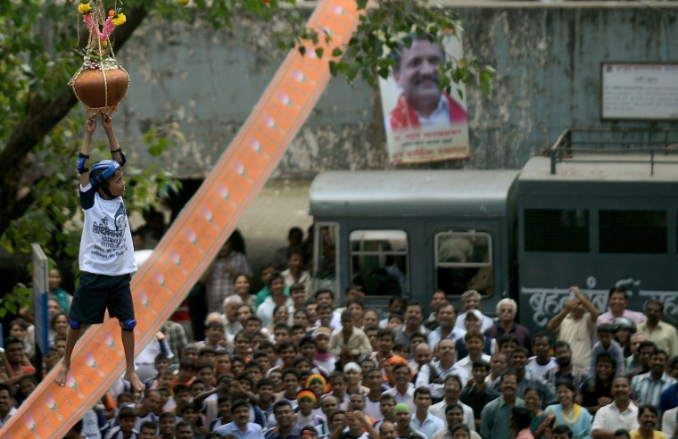 FILE - This file photograph taken on August 29, 2013 shows a young Indian Hindu devotee as he hangs onto a rope securing the dahi-handi (curd-pot) as he attempts to break the suspended vessel during celebrations of Janmashtami, which marks the birth of Hindu God Lord Krishna, in Mumbai. India's top court on August 17, 2016, has banned children from taking part in a popular but potentially dangerous religious festival in the country's west that sees young boys scale human pyramids. The Supreme Court barred children aged under 18 from scaling the pyramids and restricted their height to 20 feet (six metres) following a string of accidents in recent years. (Punit Paranjpe/AFP/Getty Images)