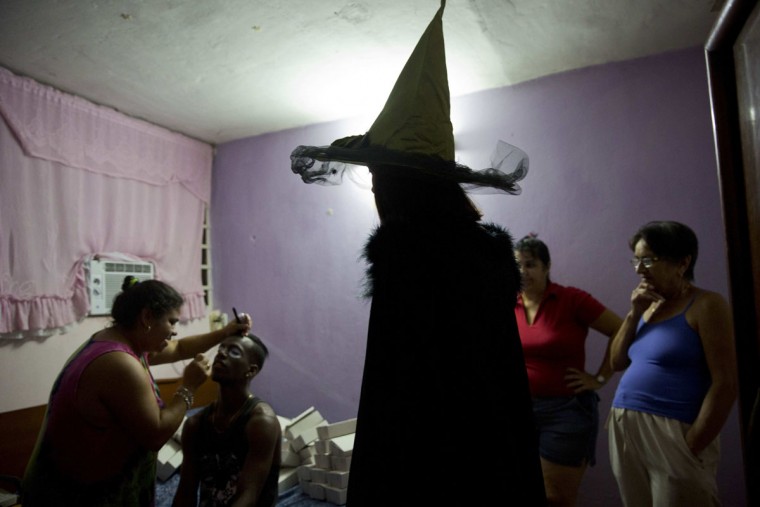Marilyn Alvarez puts makeup on her daughter's friend as they prepare for a Halloween party in Havana, Cuba, Friday, Oct. 28, 2016. Cubans are immersed in U.S. popular culture and, increasingly, U.S. products brought by expatriates visiting family on the island. (AP Photo/Ramon Espinosa)