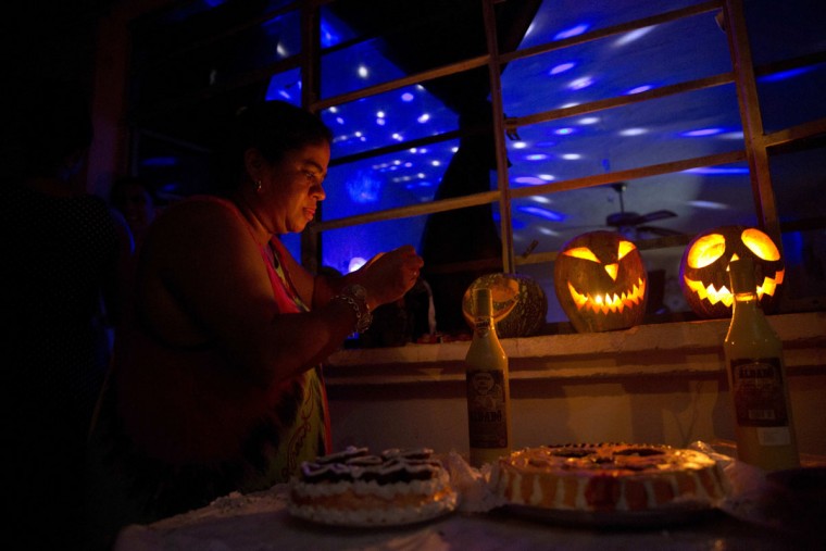 Marilyn Alvarez lights jack-o-lanterns during a Halloween party at a residence in Havana, Cuba, late Friday, Oct. 28, 2016. Inspired by pirated U.S. movies and television shows, young Cubans are turning American-style Halloween parties into the island's latest trend. (AP Photo/Ramon Espinosa)